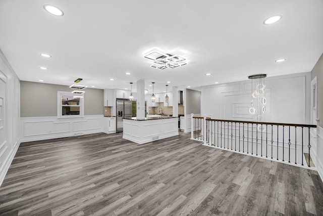 unfurnished living room with dark wood-type flooring, recessed lighting, a wainscoted wall, and a decorative wall