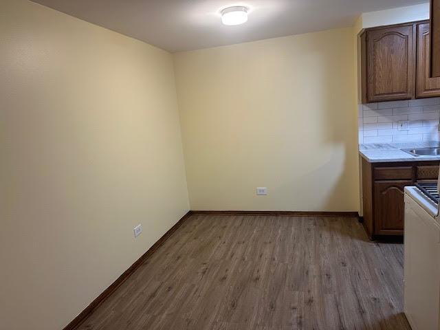 8901 N Western Ave Unit 116, Des Plaines, IL 60016 - unfurnished dining area featuring a sink, baseboards, and wood finished floors