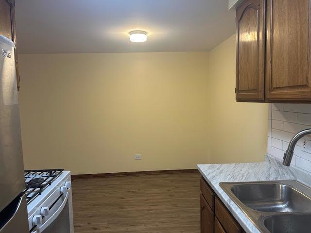 8901 N Western Ave Unit 116, Des Plaines, IL 60016 - kitchen with a sink, light countertops, dark wood finished floors, freestanding refrigerator, and gas range oven