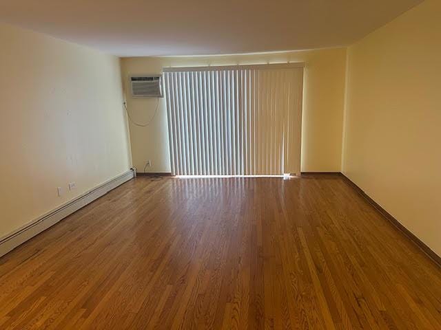 8901 N Western Ave Unit 116, Des Plaines, IL 60016 - spare room featuring baseboards, a wall mounted AC, and wood finished floors