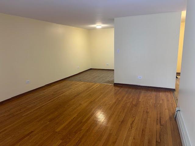 8901 N Western Ave Unit 116, Des Plaines, IL 60016 - unfurnished room with baseboards, a baseboard radiator, and wood finished floors