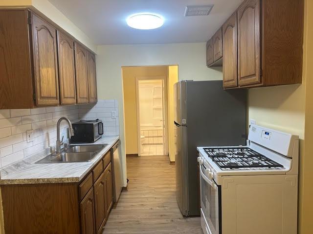 8901 N Western Ave Unit 116, Des Plaines, IL 60016 - kitchen featuring visible vents, a sink, white gas range oven, light wood finished floors, and dishwasher