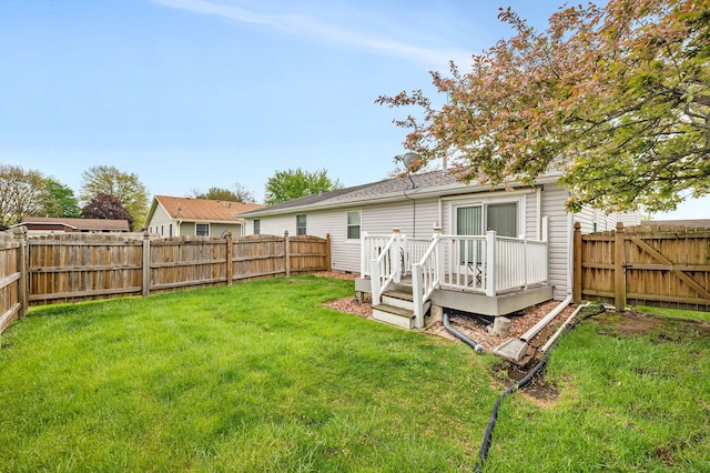 rear view of house with a fenced backyard, a lawn, and a deck