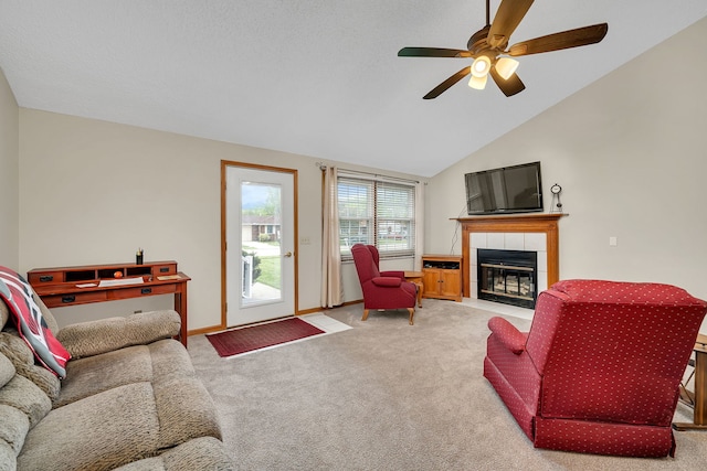 carpeted living area with baseboards, a ceiling fan, vaulted ceiling, and a fireplace