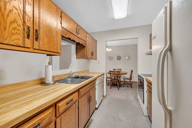 kitchen featuring brown cabinetry, light carpet, white appliances, a textured ceiling, and a sink