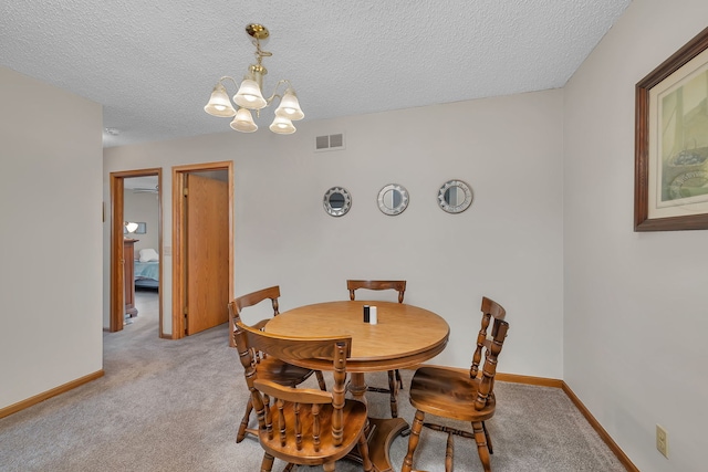 dining space featuring carpet, a notable chandelier, a textured ceiling, and visible vents