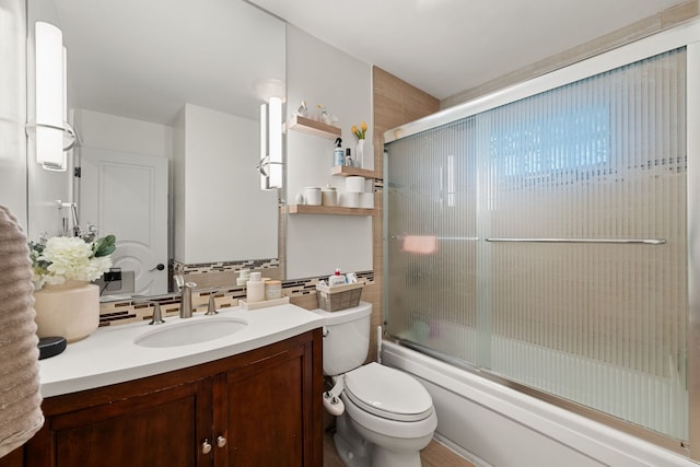 full bathroom featuring vanity, decorative backsplash, combined bath / shower with glass door, and toilet