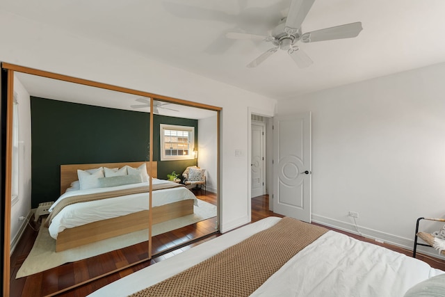 bedroom featuring a ceiling fan, baseboards, wood finished floors, and a closet