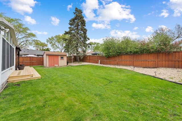 view of yard with a fenced backyard, a storage unit, an outdoor structure, and a wooden deck