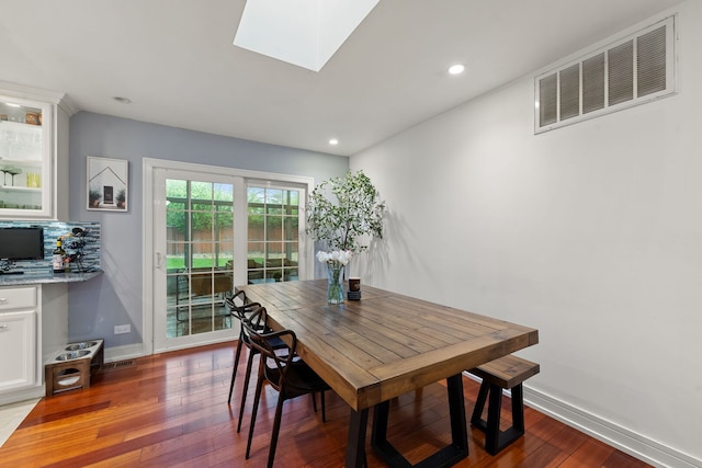 dining room featuring dark wood-style flooring, recessed lighting, baseboards, a skylight, and visible vents