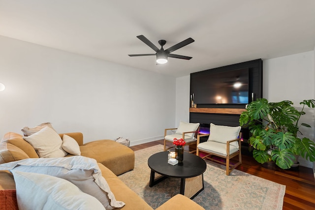living room featuring a ceiling fan, baseboards, and wood finished floors