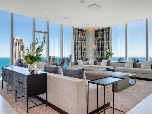 living area featuring expansive windows, a water view, light tile patterned floors, and visible vents