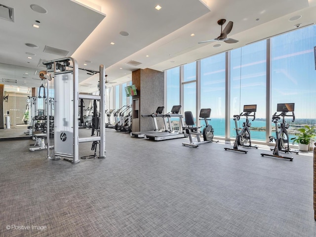 exercise room with a wall of windows, a ceiling fan, and visible vents