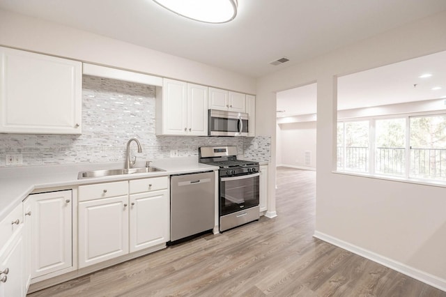 kitchen featuring a sink, stainless steel appliances, white cabinets, visible vents, and backsplash