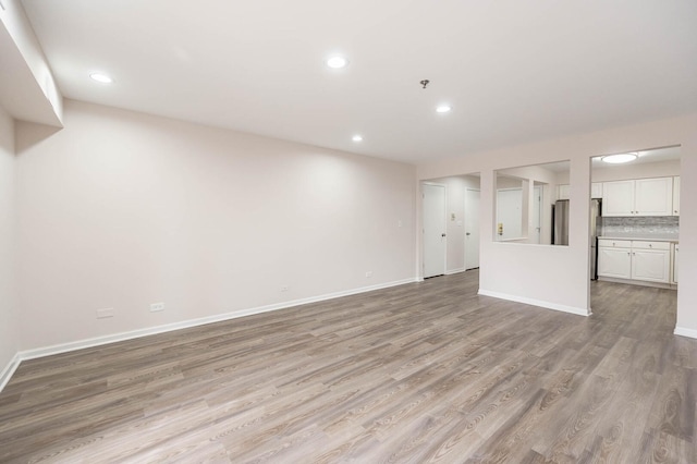 unfurnished living room with baseboards, light wood finished floors, and recessed lighting