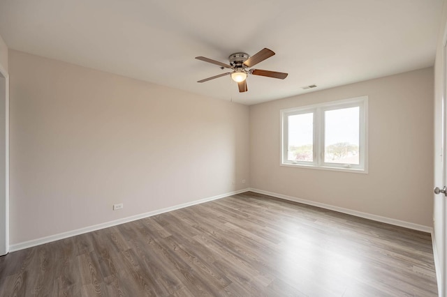spare room with a ceiling fan, baseboards, dark wood finished floors, and visible vents