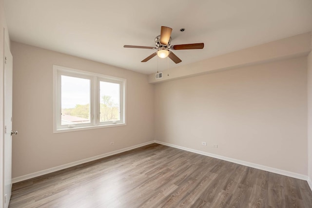 unfurnished room with baseboards, ceiling fan, visible vents, and wood finished floors