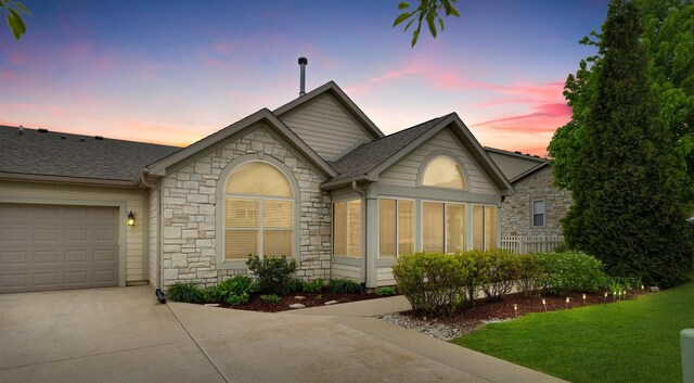 2715 J T Coffman Dr Unit 2715, Champaign, IL 61822 - ranch-style house featuring stone siding, concrete driveway, roof with shingles, a lawn, and a garage
