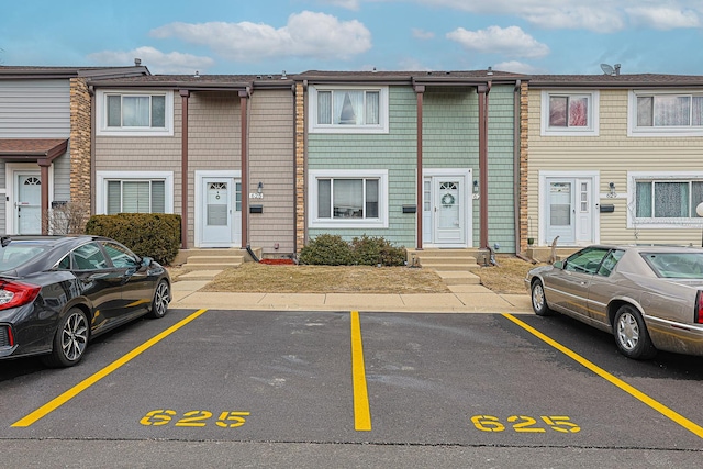 view of property with uncovered parking and entry steps