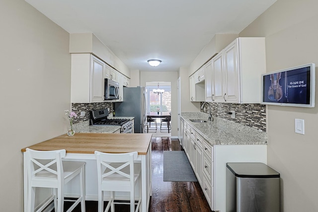 kitchen with tasteful backsplash, a sink, dark wood finished floors, appliances with stainless steel finishes, and a notable chandelier