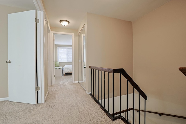 corridor featuring baseboards, carpet flooring, and an upstairs landing