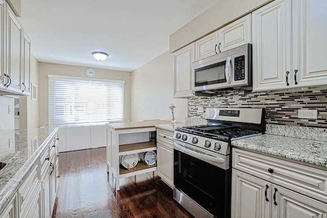 kitchen featuring white cabinets, light stone countertops, stainless steel appliances, tasteful backsplash, and dark wood-style floors
