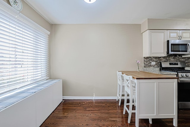 kitchen featuring decorative backsplash, butcher block countertops, white cabinetry, dark wood finished floors, and appliances with stainless steel finishes