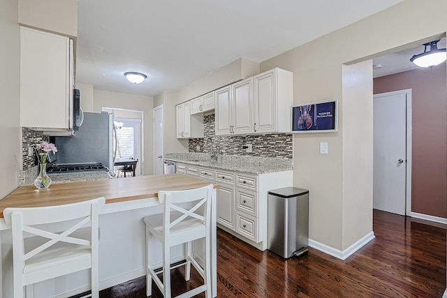kitchen with light countertops, decorative backsplash, dark wood-style floors, and white cabinets
