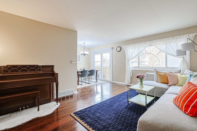 living area featuring baseboards, an inviting chandelier, wood finished floors, and visible vents