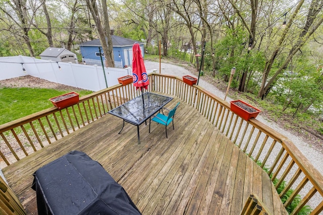 deck with outdoor dining space and view of wooded area