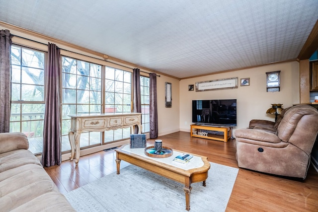living area featuring light wood-style floors, ornamental molding, and baseboards