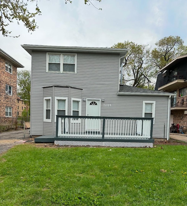 back of property featuring a wooden deck and a yard