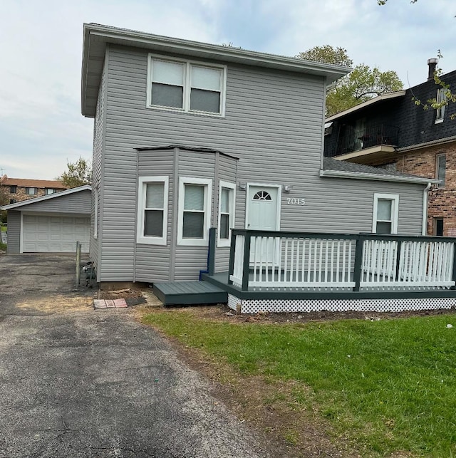 back of property with a detached garage, an outdoor structure, and a deck