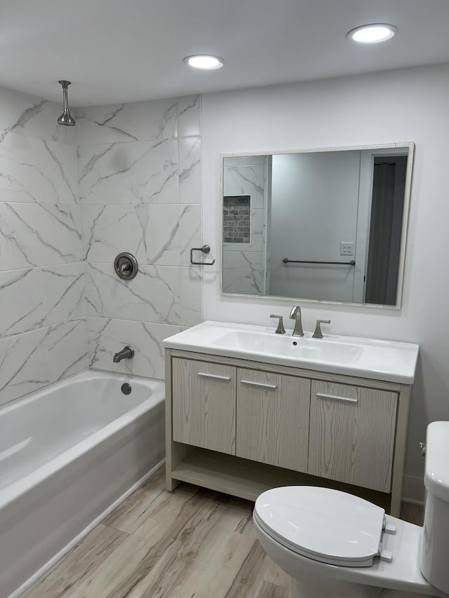 bathroom featuring vanity, toilet, recessed lighting, shower / washtub combination, and wood finished floors