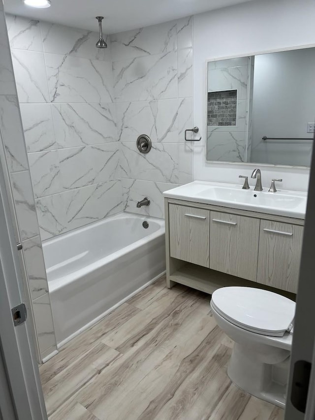 bathroom with a combined bath / shower with rainfall shower, wood finished floors, toilet, and vanity