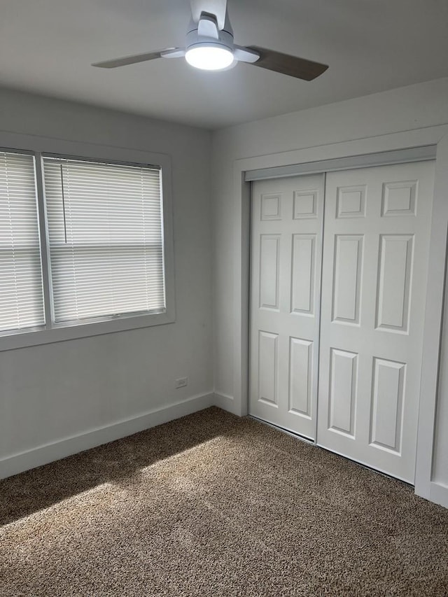 unfurnished bedroom featuring baseboards, ceiling fan, carpet, and a closet