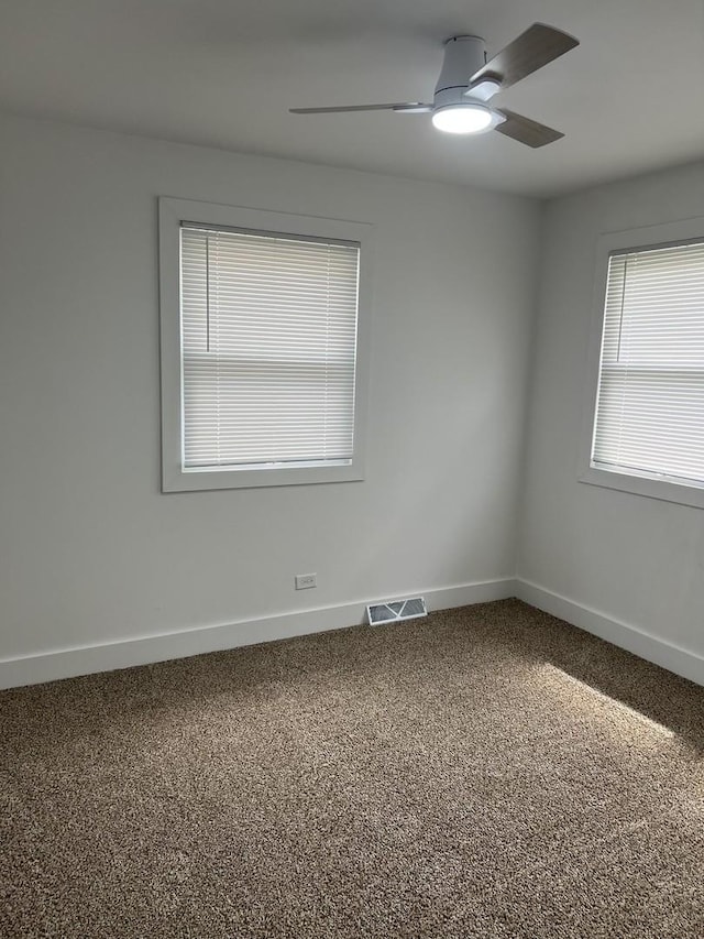 carpeted empty room with visible vents, baseboards, and ceiling fan