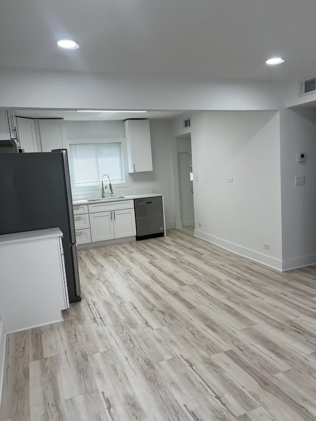 kitchen featuring visible vents, freestanding refrigerator, dishwashing machine, light wood-type flooring, and a sink