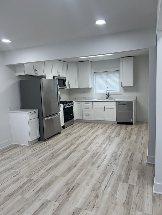 kitchen with a sink, light countertops, stainless steel appliances, and light wood-type flooring