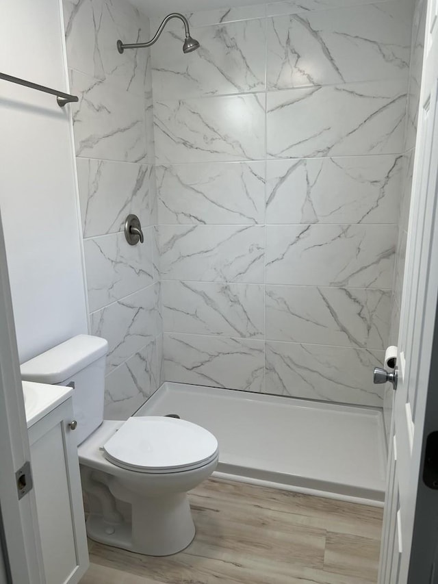 bathroom with vanity, a shower stall, toilet, and wood finished floors