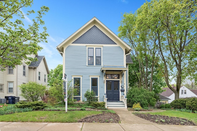 victorian house featuring central air condition unit and a front yard