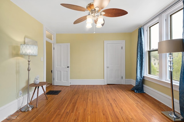 interior space featuring baseboards, light wood-style flooring, visible vents, and a ceiling fan