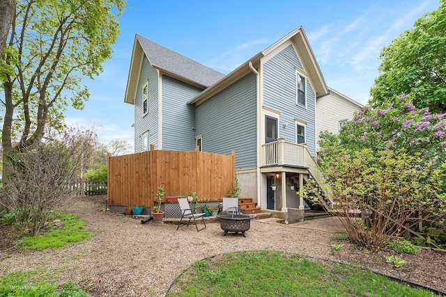 back of property with an outdoor fire pit, fence, and a patio