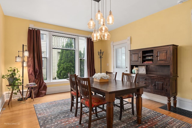 dining room with baseboards, light wood-style flooring, and a chandelier