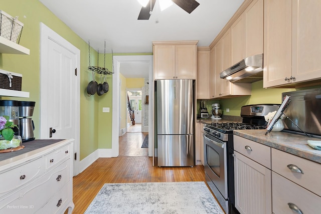 kitchen featuring stainless steel appliances, light wood-type flooring, baseboards, ceiling fan, and under cabinet range hood