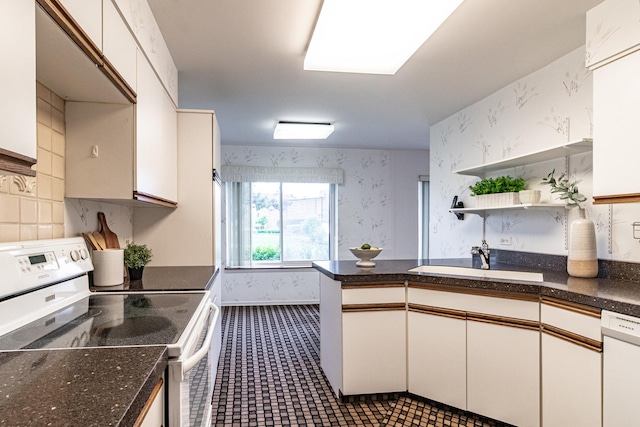 kitchen with open shelves, a sink, a peninsula, wallpapered walls, and white appliances