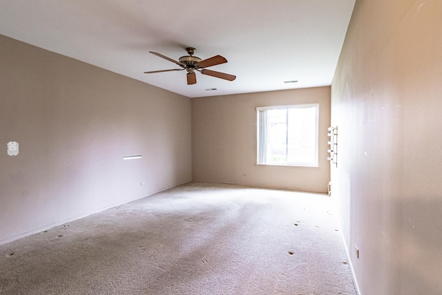 unfurnished room with carpet floors, baseboards, a ceiling fan, and visible vents