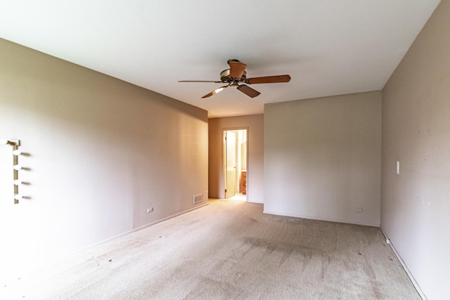 unfurnished room featuring light colored carpet, a ceiling fan, baseboards, and visible vents