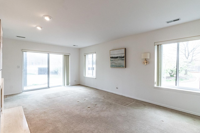 unfurnished living room featuring baseboards, visible vents, and carpet