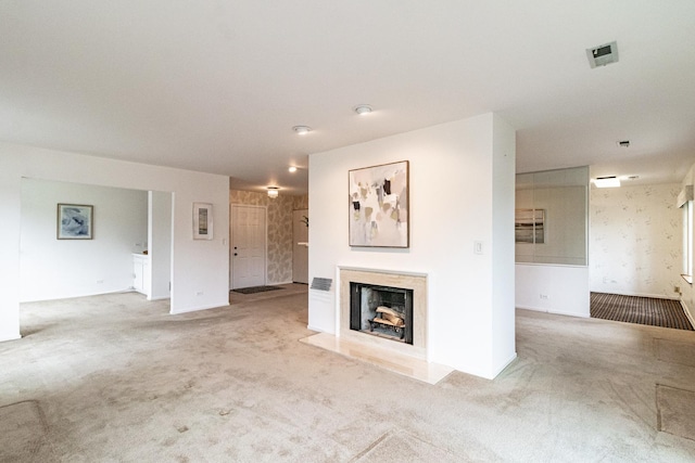 unfurnished living room with visible vents, carpet, baseboards, and a fireplace